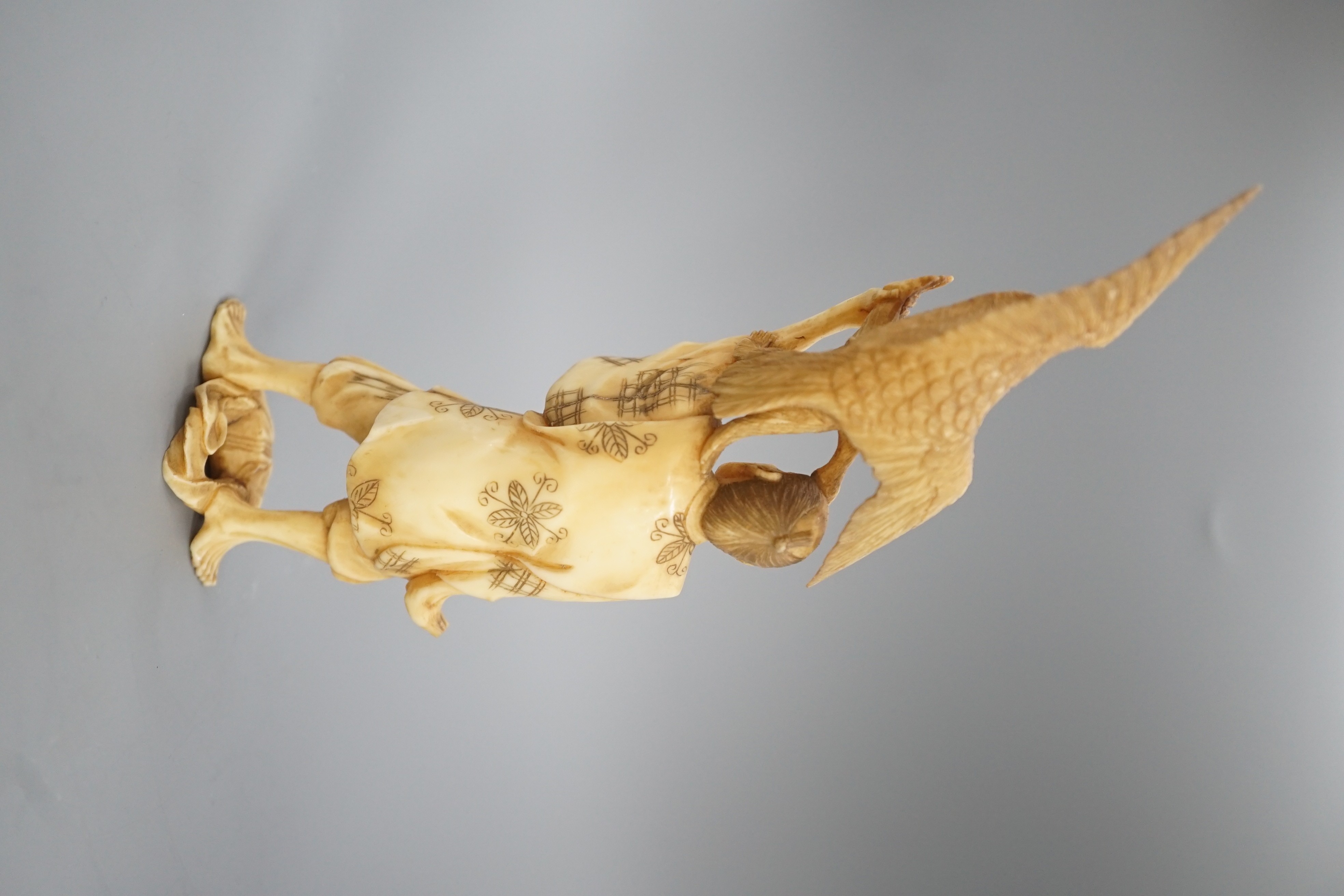 A Japanese ivory okimono of a man holding a monkey which is being attacked by an eagle, early 20th century 15.5cm